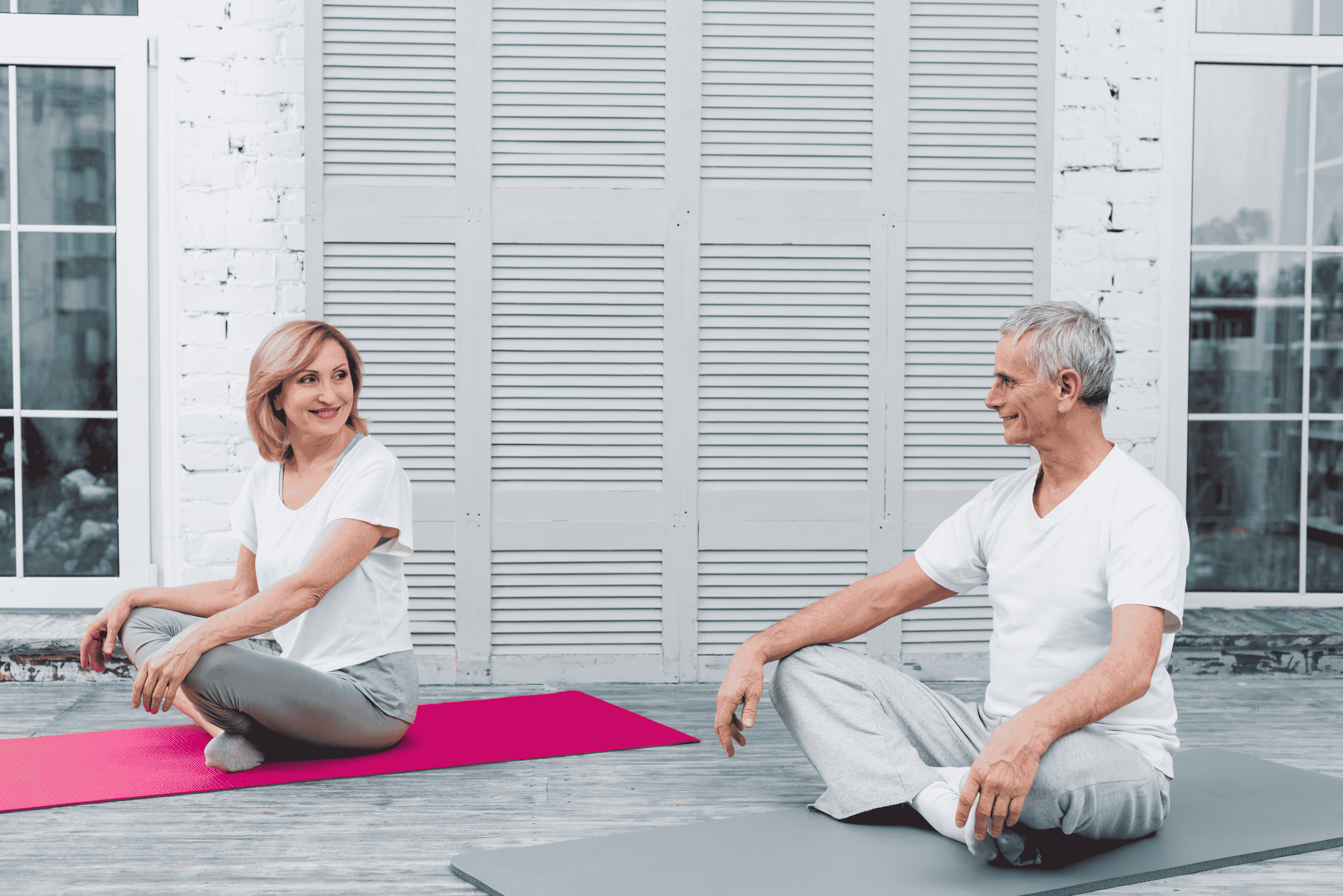 Two seniors sitting on exercise mats